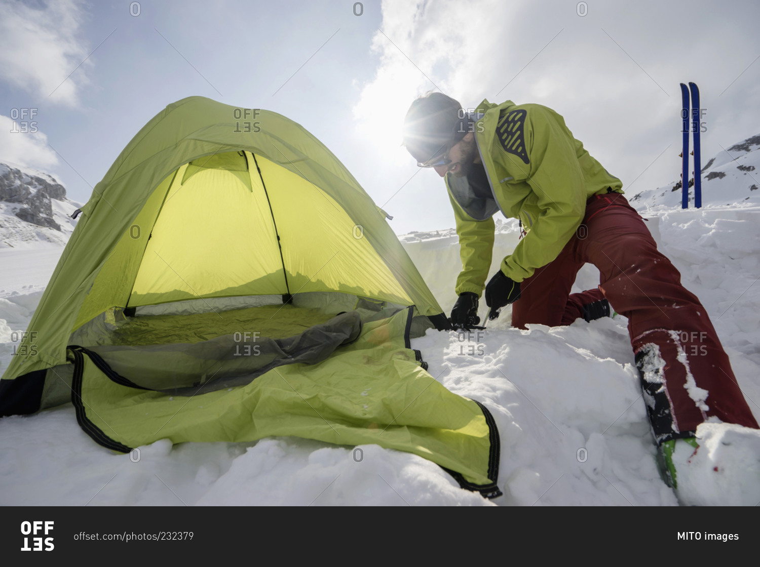 Man constructing tent in snow