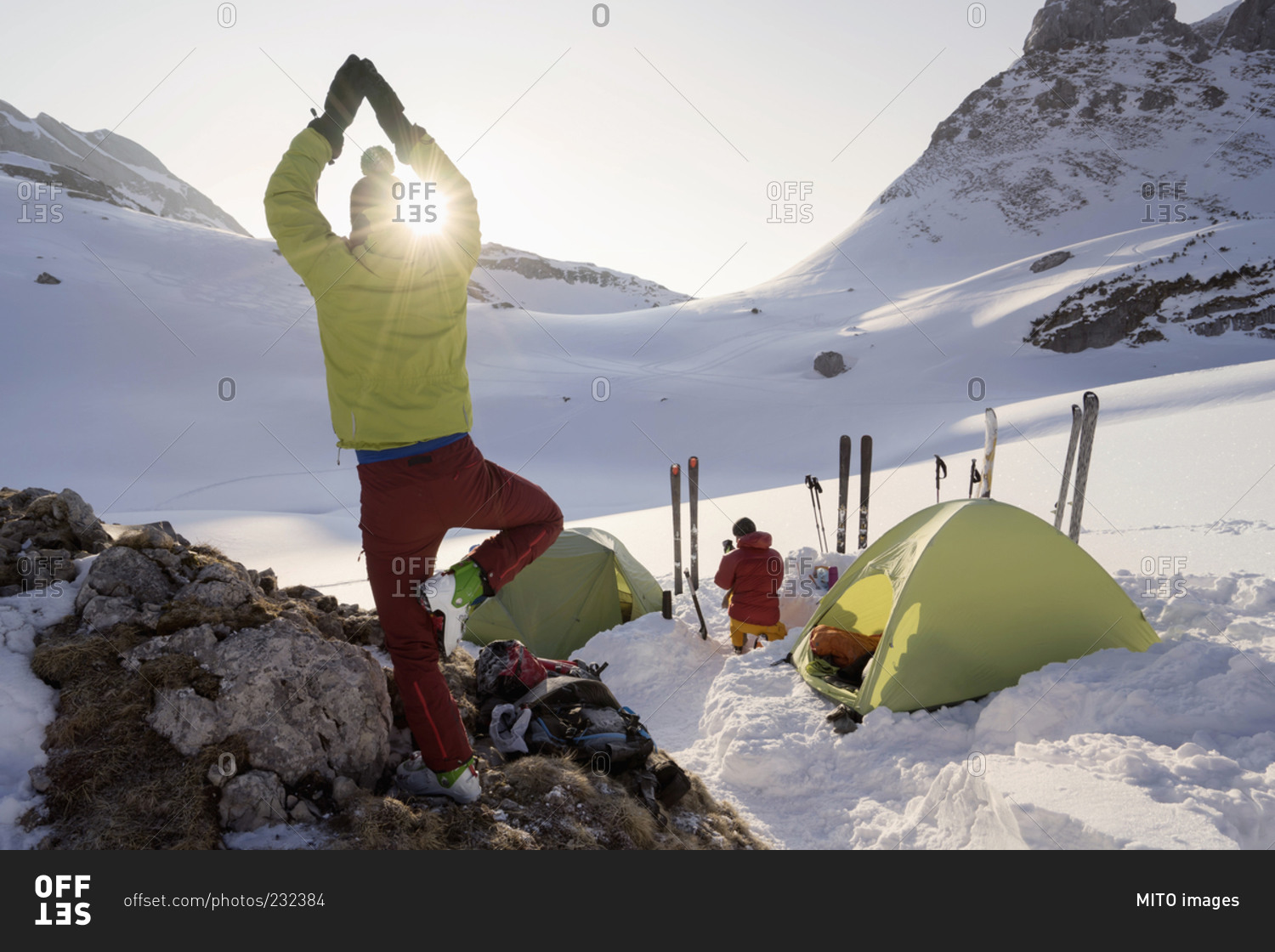 Rear view of man doing yoga at sunrise while camping on mountain
