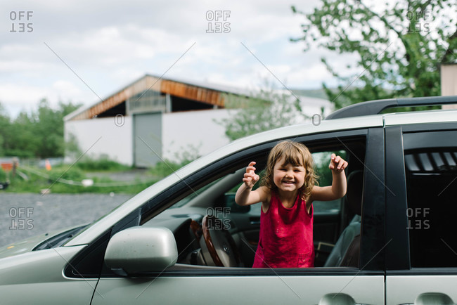 Little girl waving from the front seat of a car