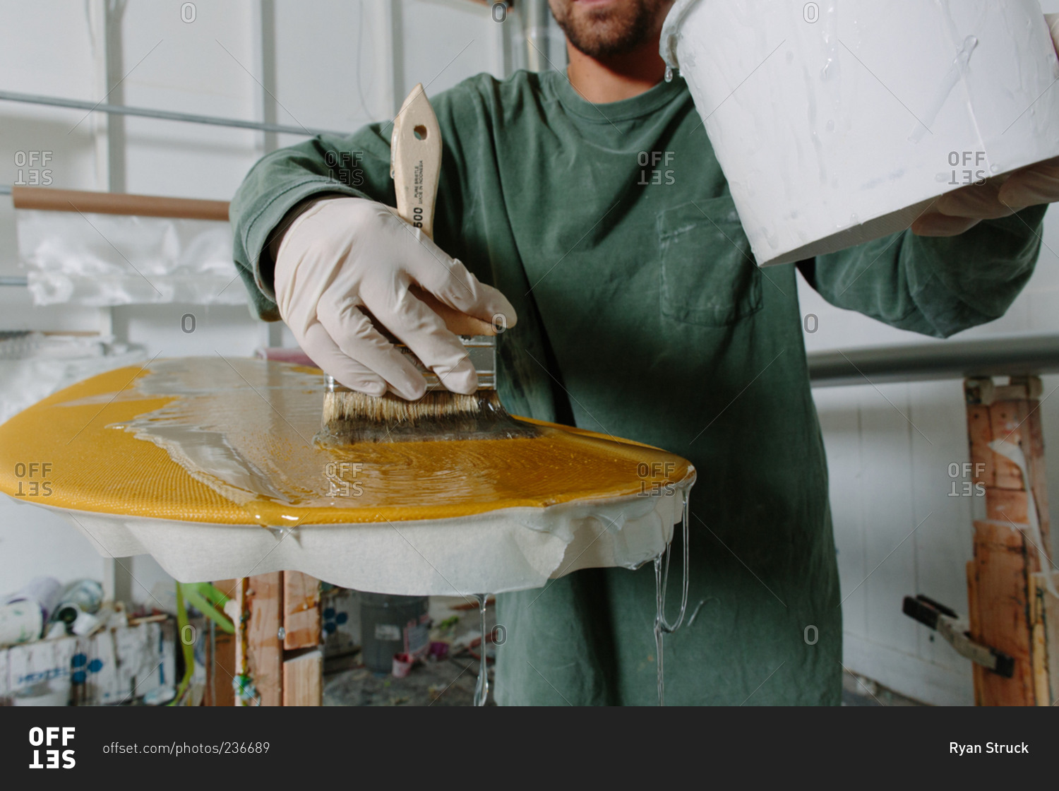 A craftsman brushes a clear coating on a custom surfboard stock photo