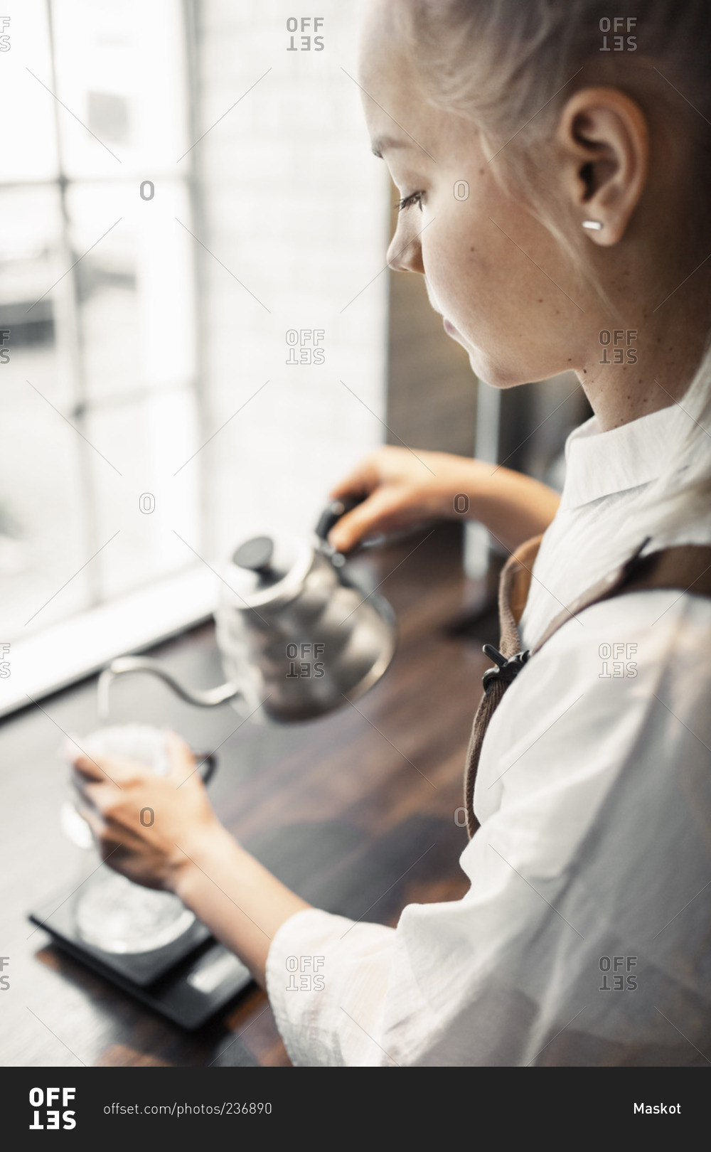 Side view of barista pouring boiling water in coffee filter