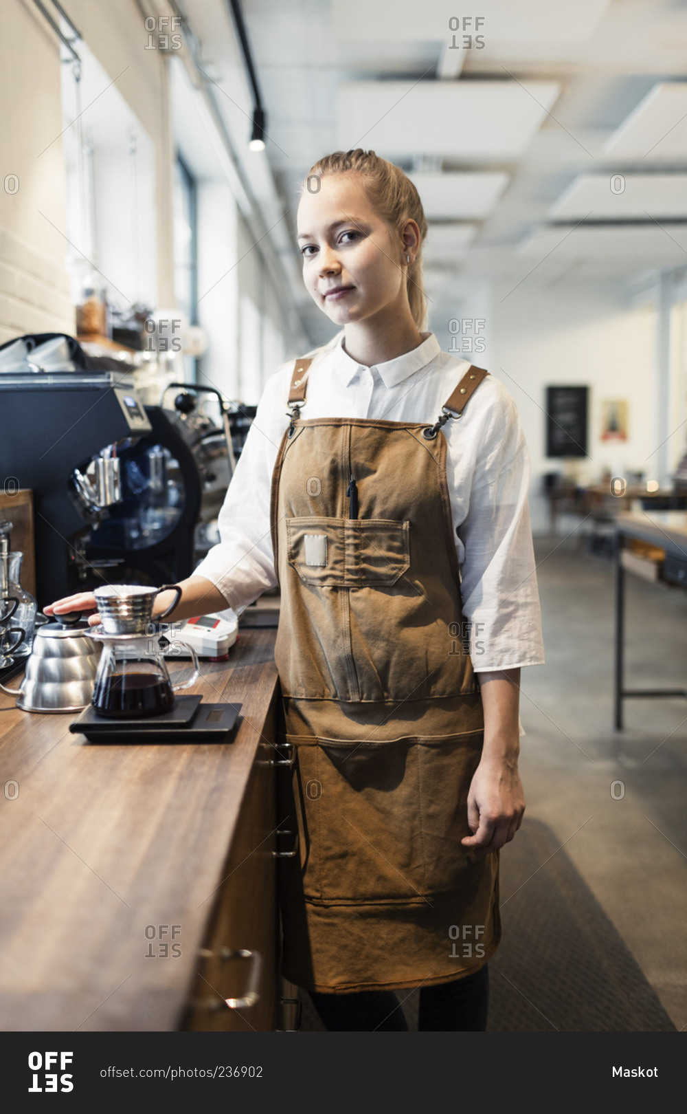 Portrait of confident female barista standing at counter in coffee shop