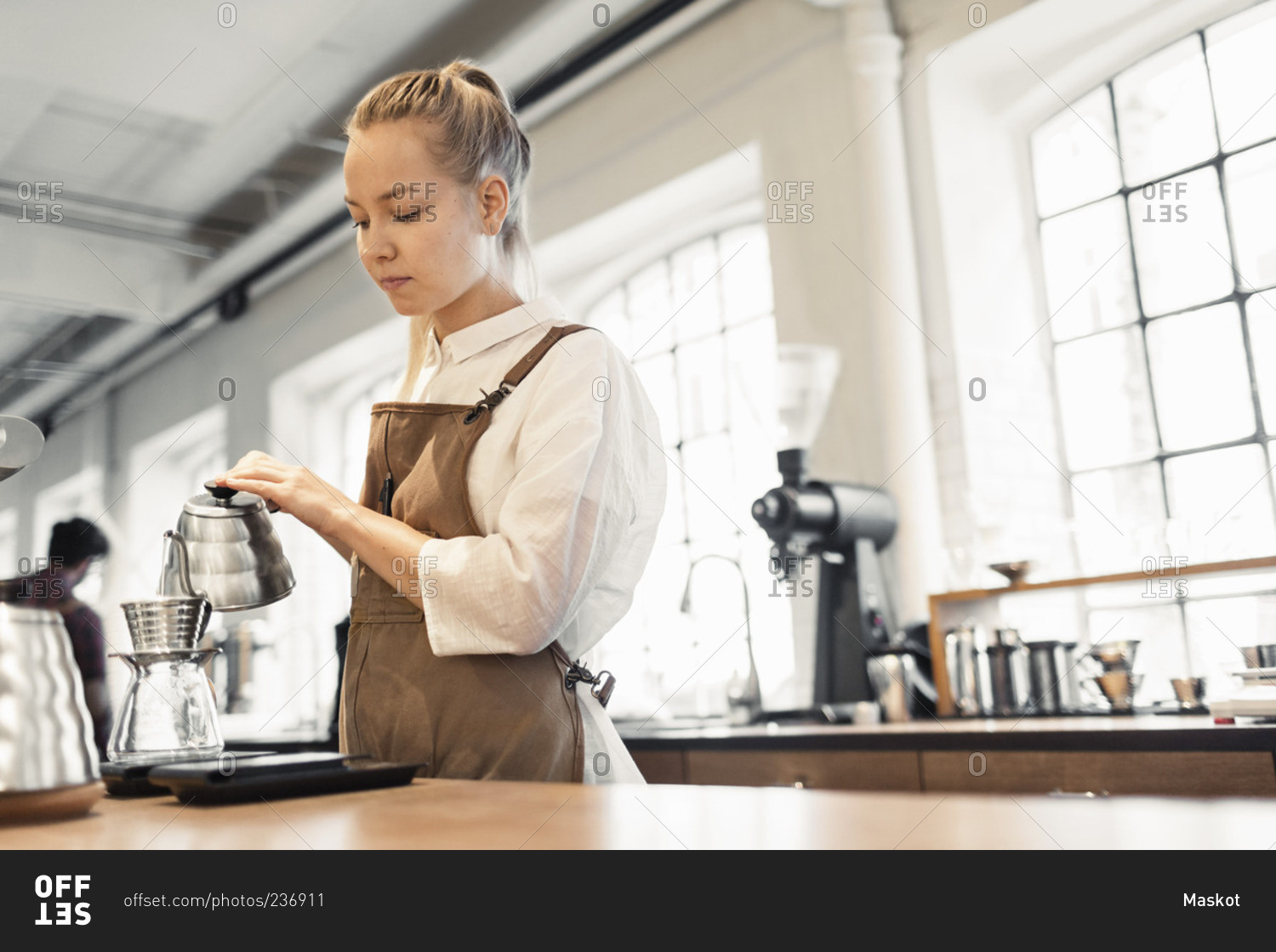 Female barista pouring boiling water in coffee filter at cafe