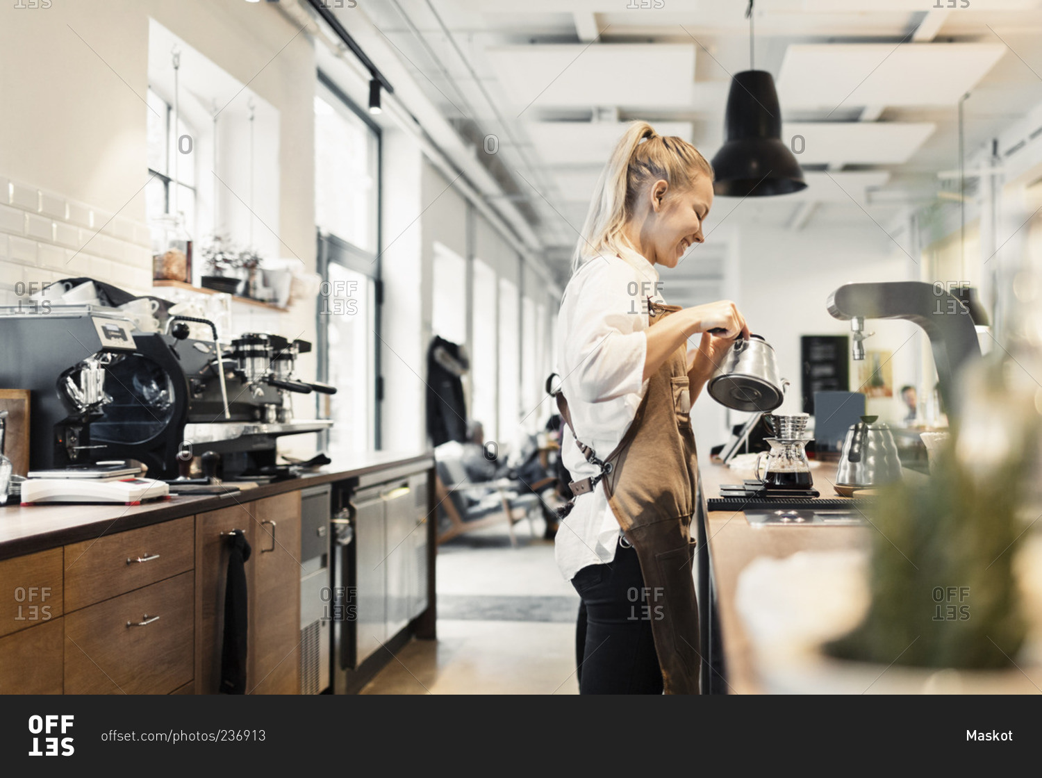 Side view of female barista preparing coffee at counter