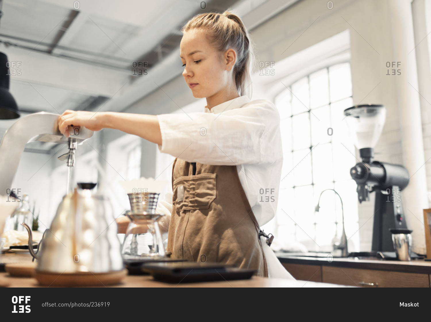 Young female worker preparing coffee at counter