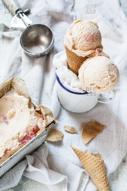 Vanilla ice-cream with fruit swirl in loaf pan, emaille cup with ice-cream cone and ice scoops, ice cream scoop