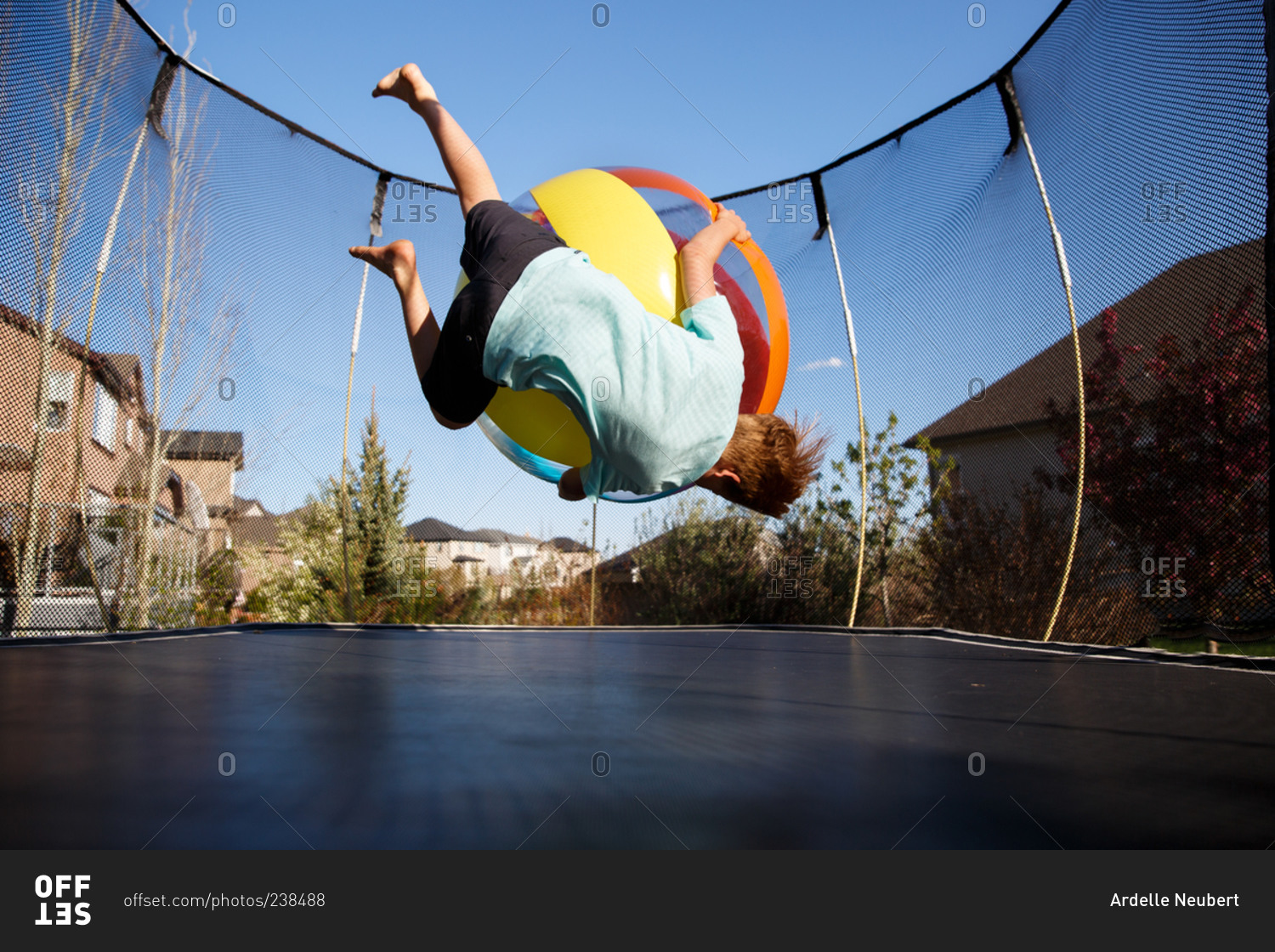 Boy playing on a trampoline with a ball stock photo OFFSET