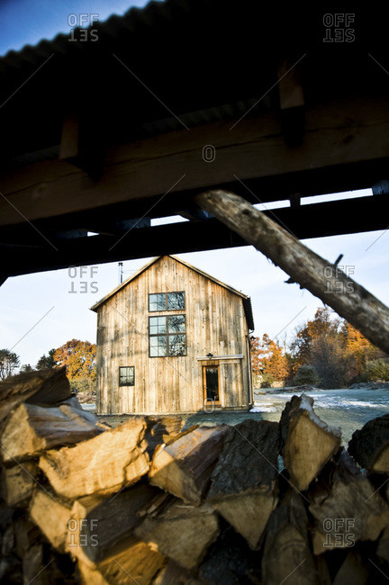 A barn with mushroom wood siding next to a wood shed