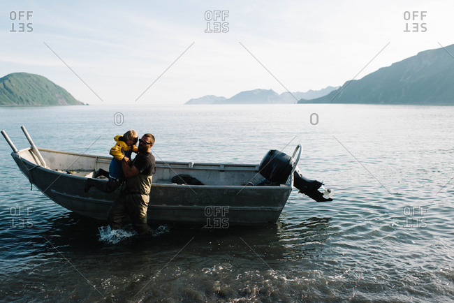 Fisherman lifting child out of boat
