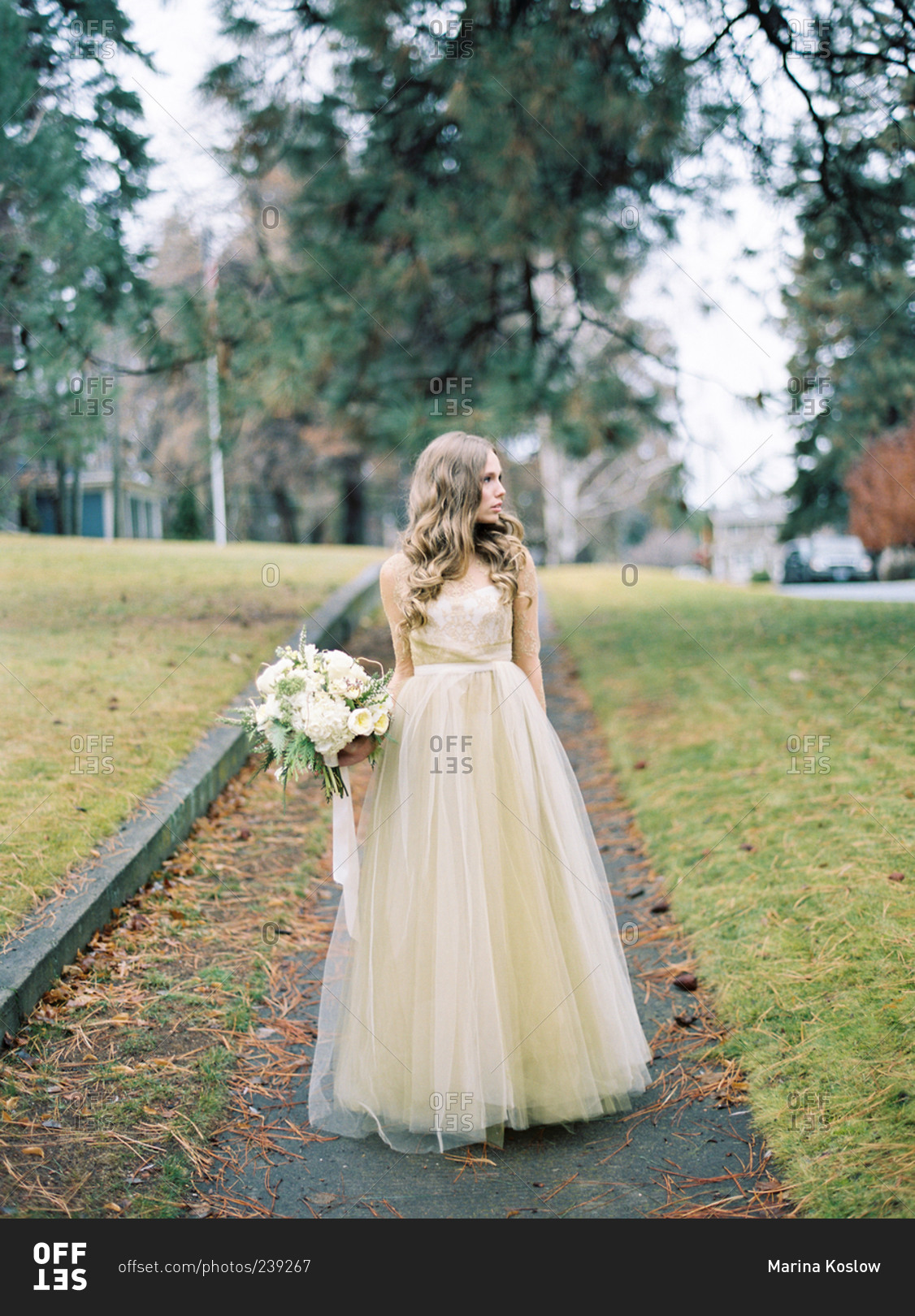 Bride standing on wet fall street looking to the side
