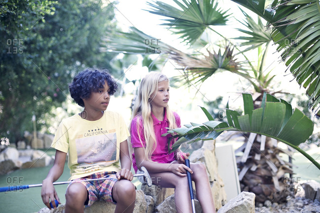 Adolescents sitting while playing minigolf