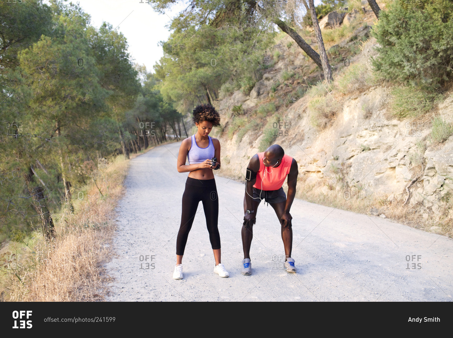 Athletic couple setting time on rural road