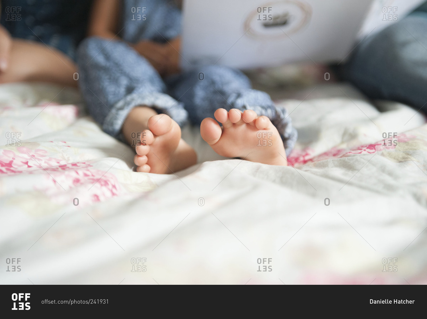 Child's feet on a bed stock photo - OFFSET