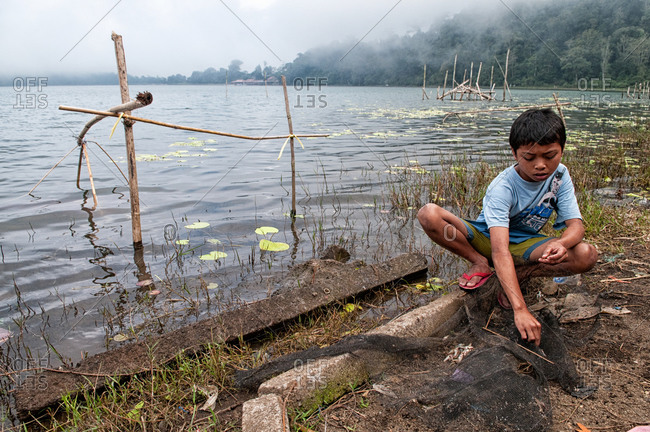 Bratan Lake, Indonesia - May 29, 2015: A young boy fishing