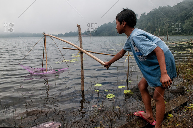 Bratan Lake, Indonesia - May 29, 2015: Young boy fishing with a rod