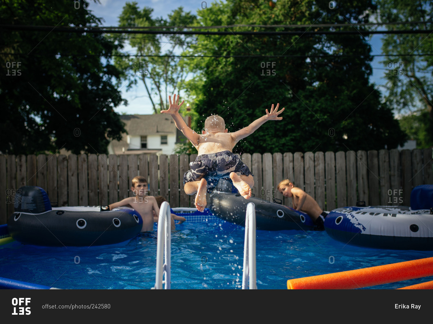 Boy jumping into pool with friends stock photo OFFSET