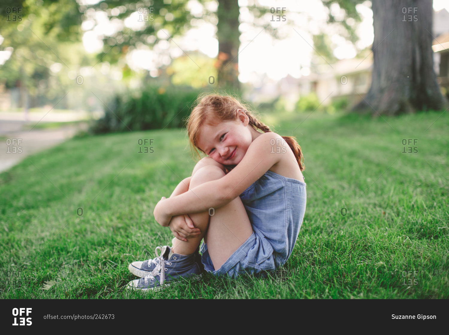 Little girl hugging her knees and smiling stock photo - OFFSET