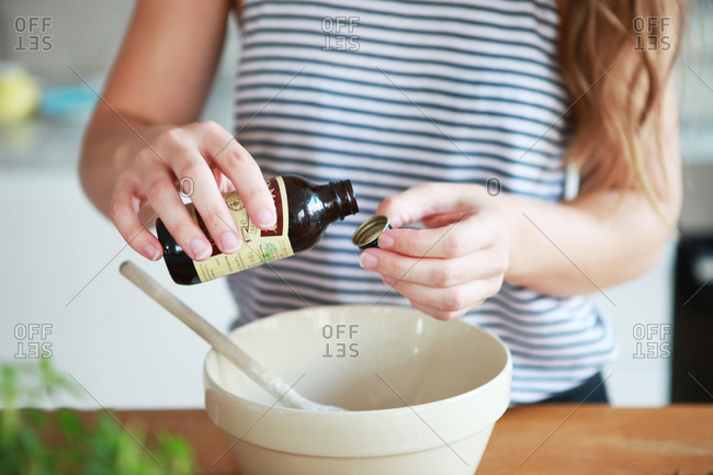 A woman measures vanilla into a bowl