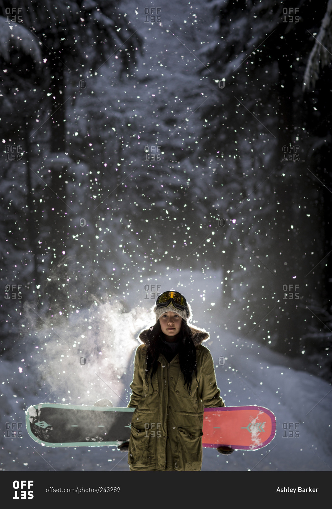 Female snowboarder holding board at night