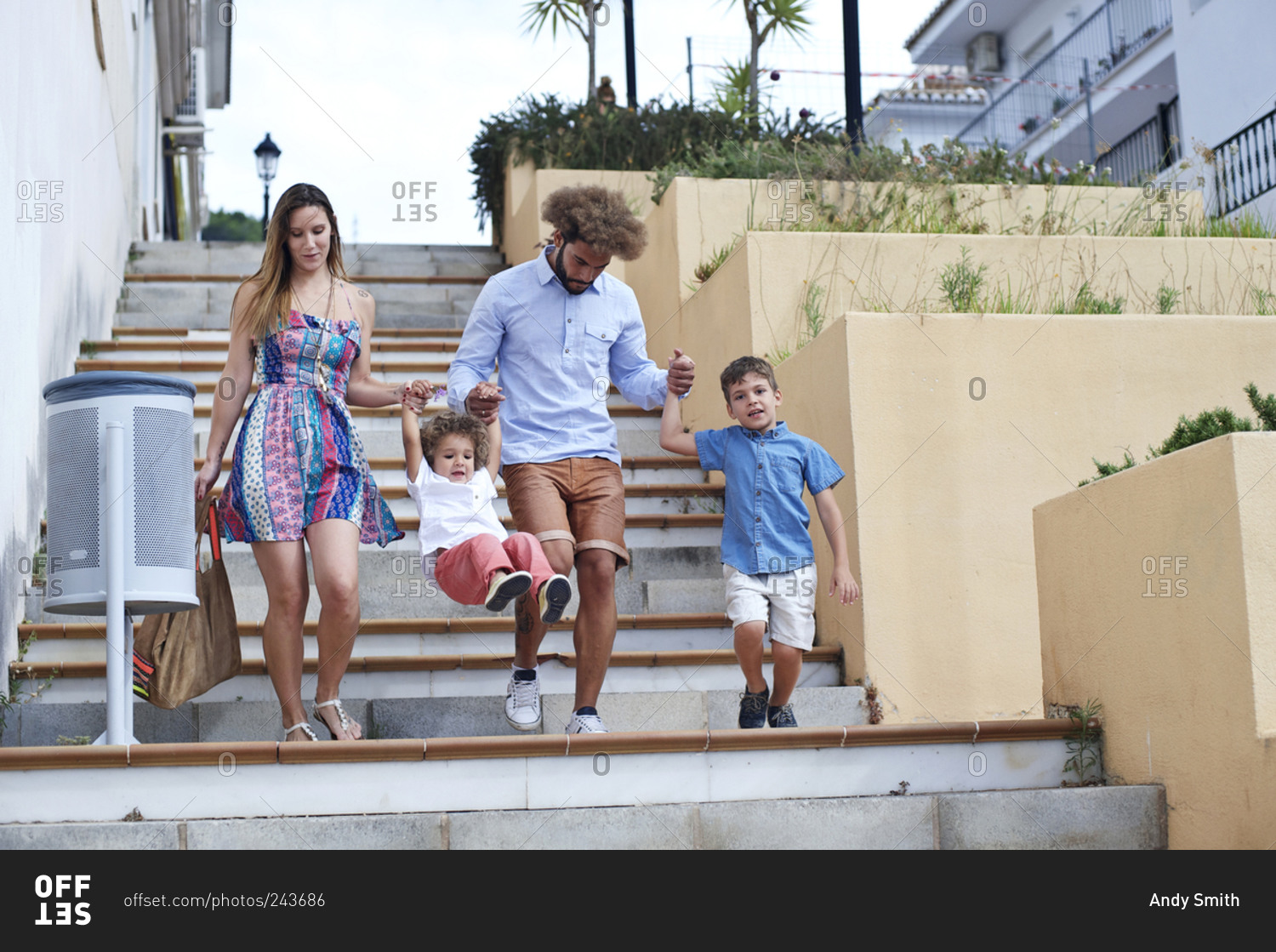 Family of four walking down steps in a coastal southern European hillside town