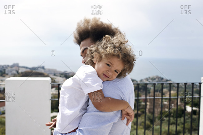 Father holding tired son at a scenic overlook by the sea