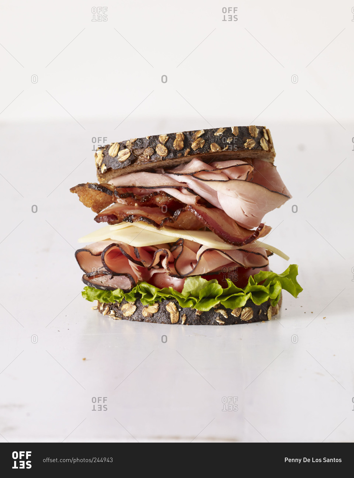 Side view of a generous sandwich with ham, cheese, turkey and bacon
