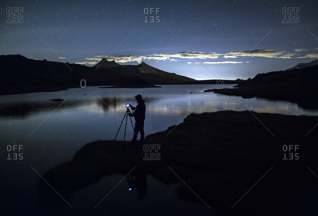 Photographer admires reflection on Rossett Lake at night, Gran Paradiso National Park, Alpi Graie (Graian Alps), Italy, Europe