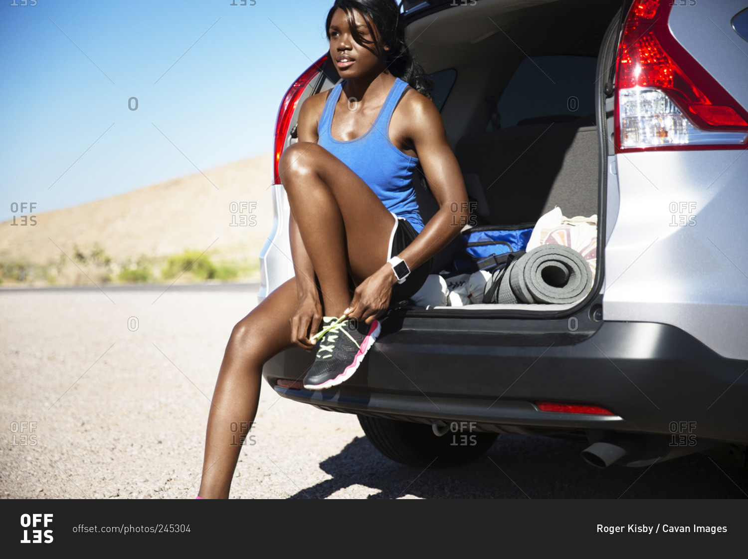 Woman sitting in van tying shoes for workout