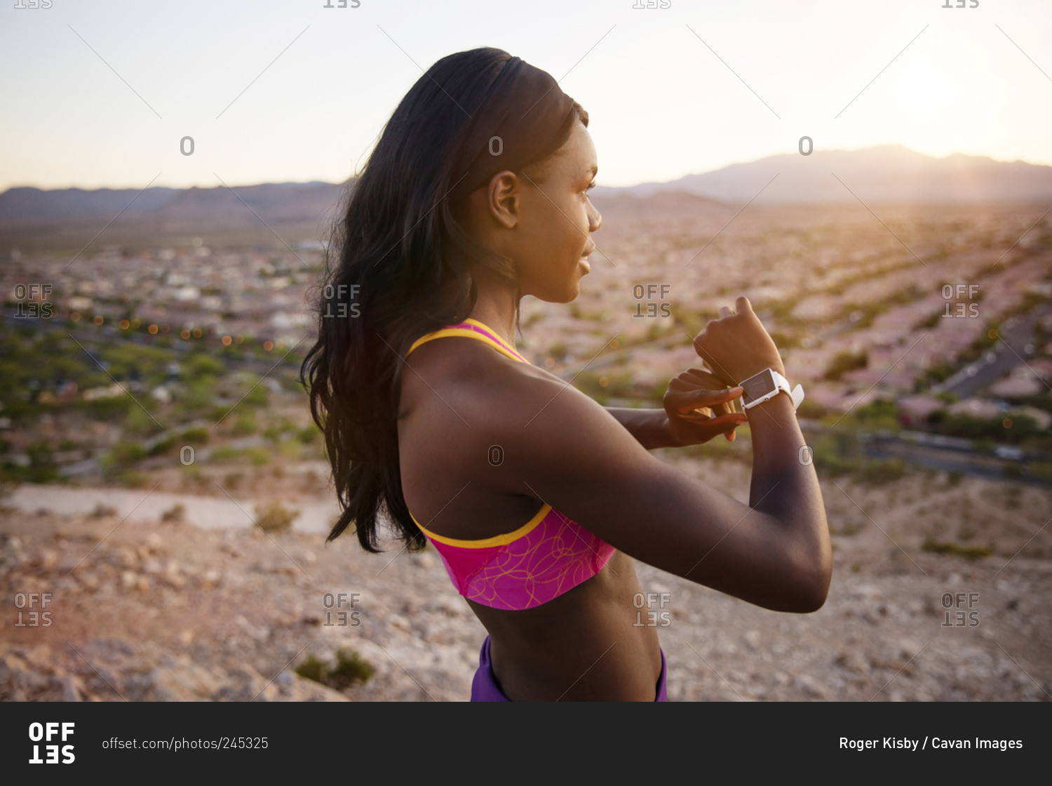 Athletic woman on desert hills checking fitness tracker