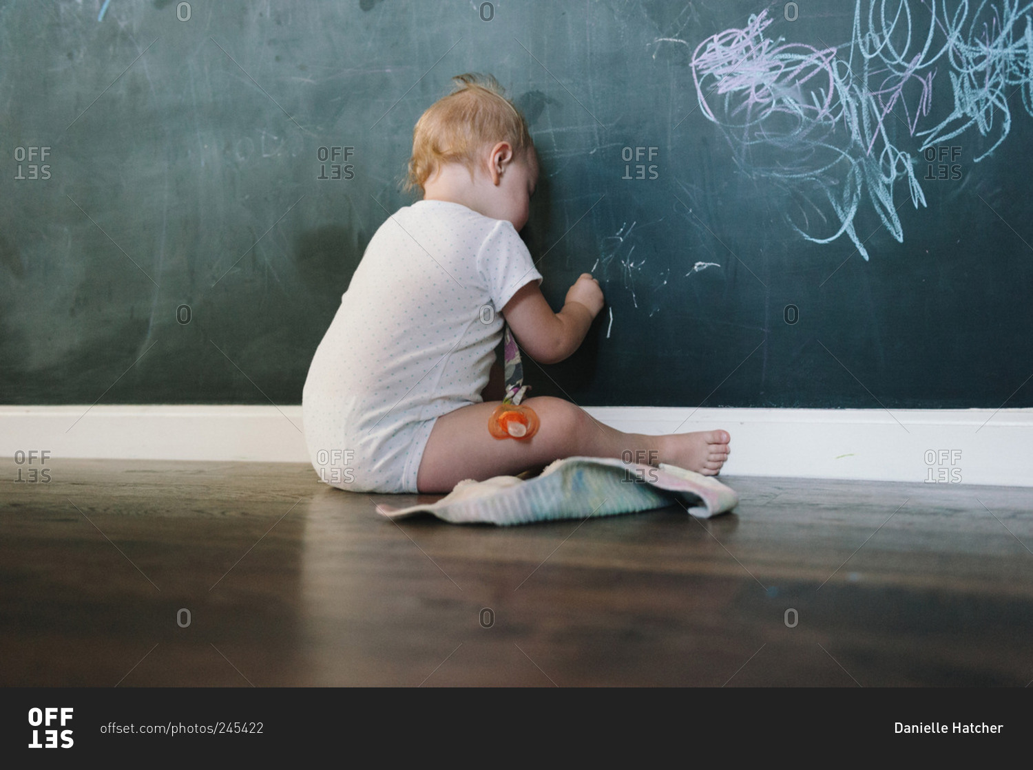 A baby draws on a wall with chalk
