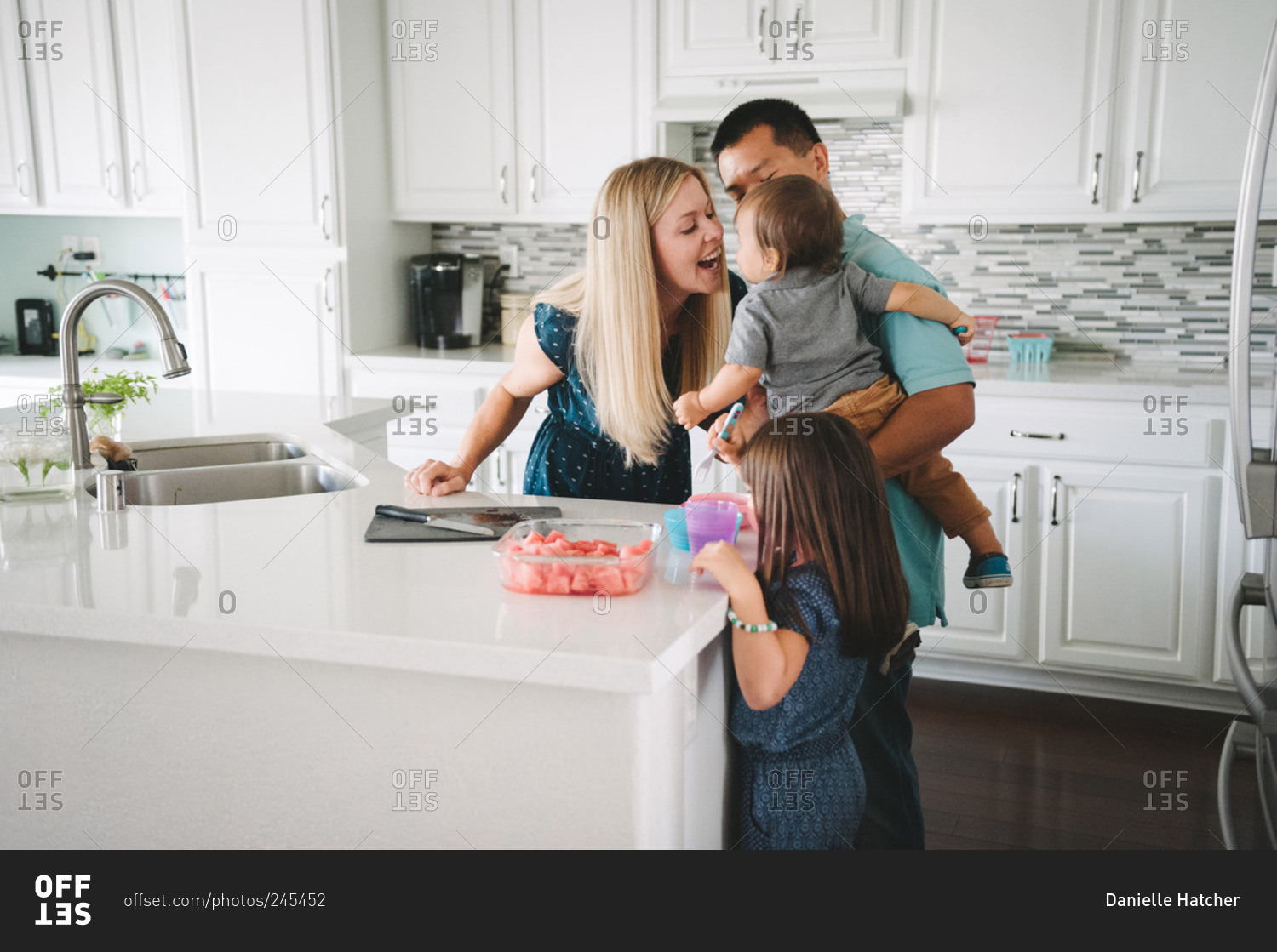 A family gathers in the kitchen for a watermelon snack