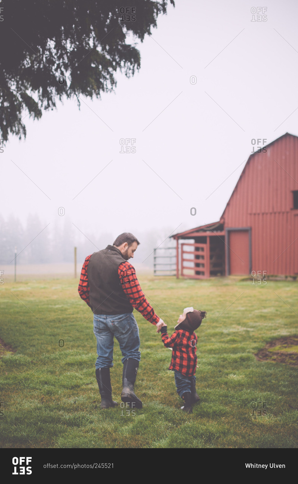 Portrait of father and son wearing matching plaid flannel shirts on misty farm