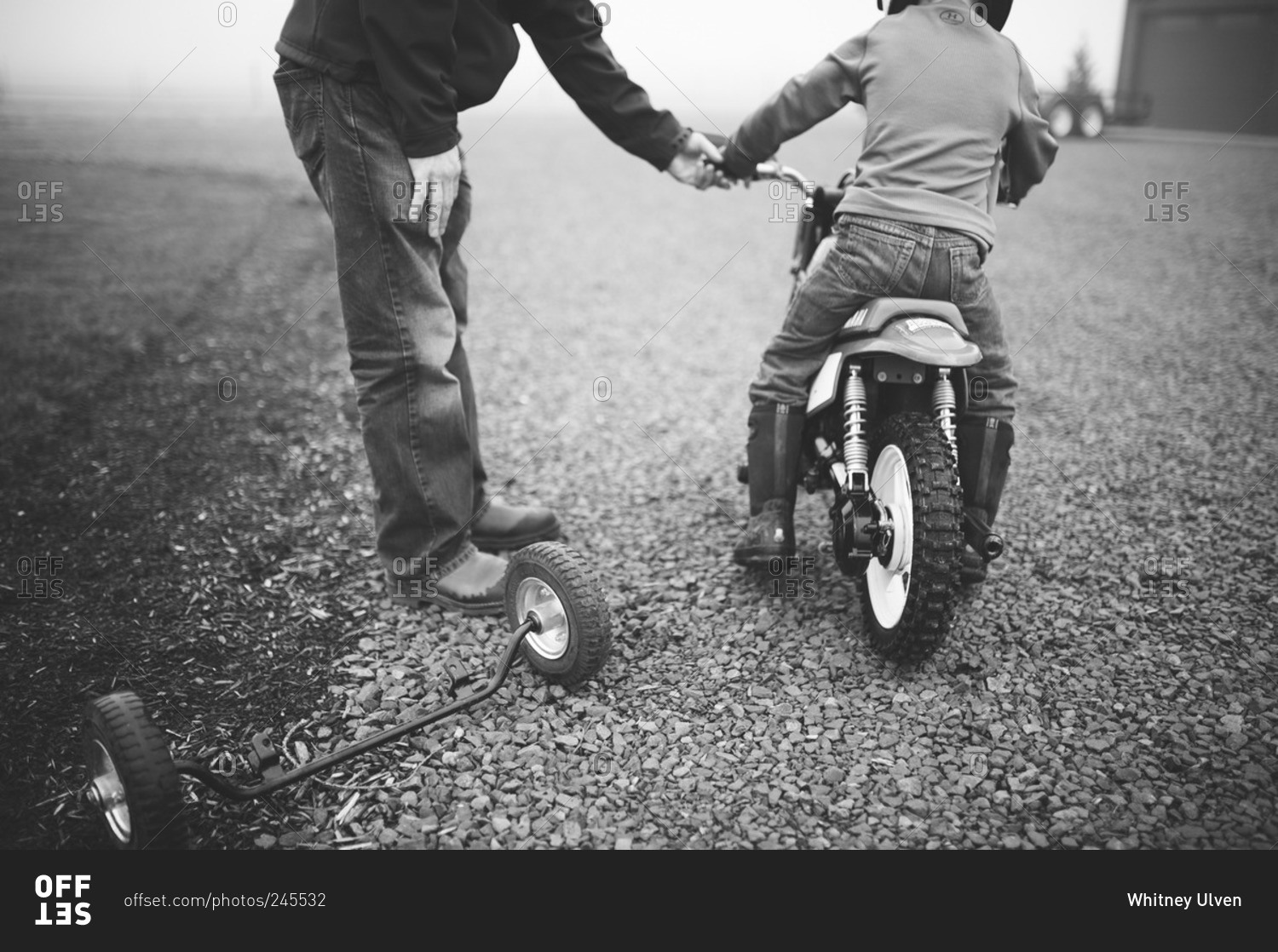 Man helping boy on his youth sized dirt bike