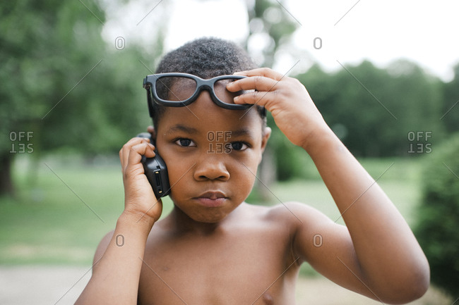 Little boy on cell phone lifting his glasses