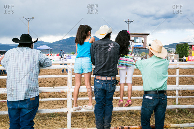 Men and little girls standing at a rodeo fence