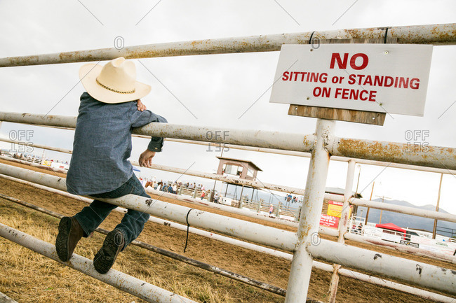 Boy sitting on a rodeo fence