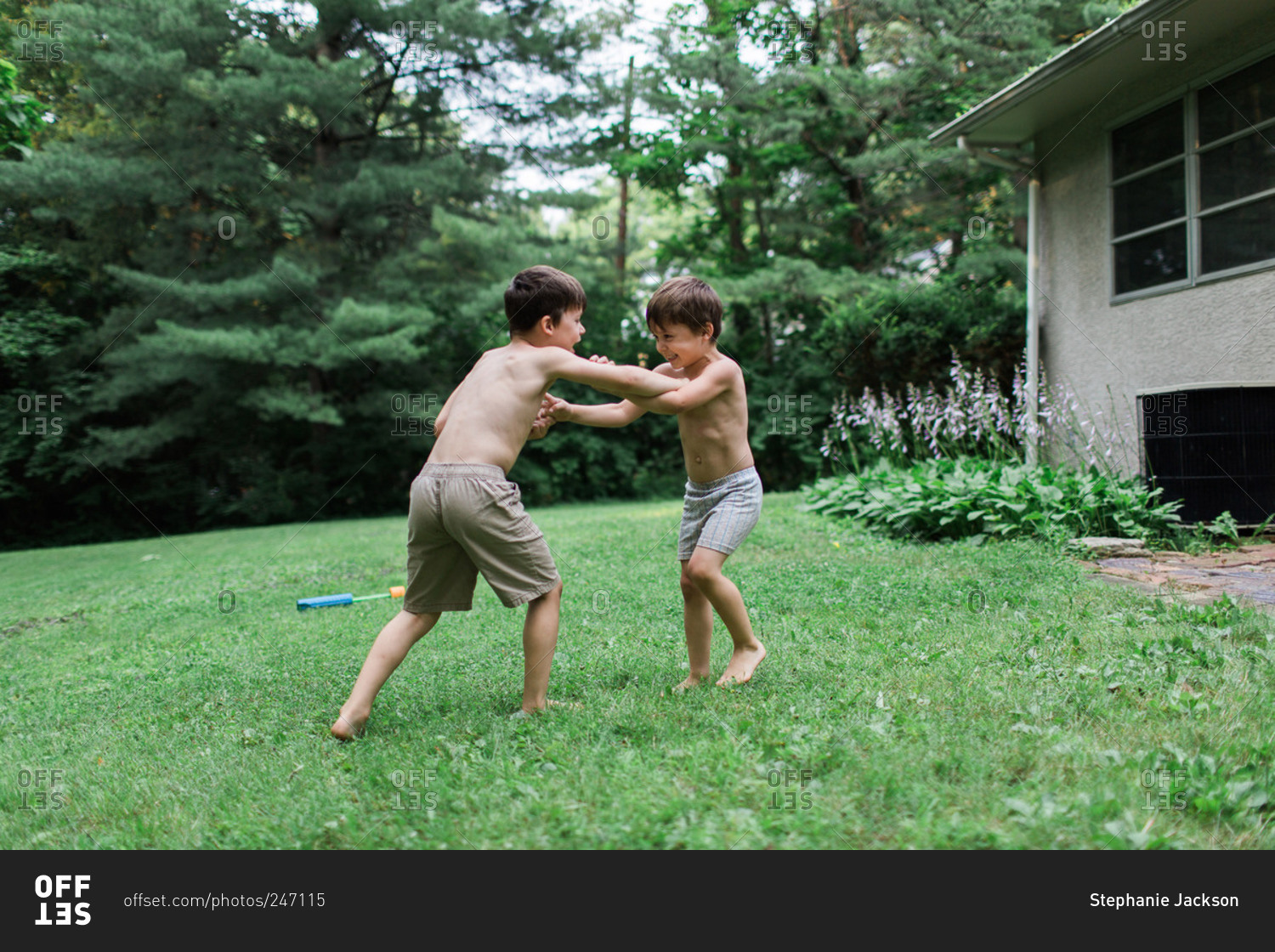 Two young brothers wrestle in their backyard