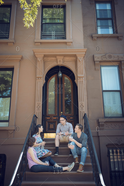 Friends hang out on the steps of a brownstone