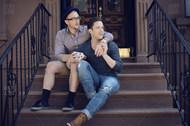 A couple sitting on the stairs of a brownstone