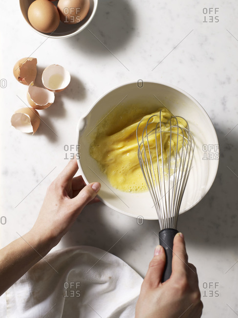 Hands beating eggs with a whisk