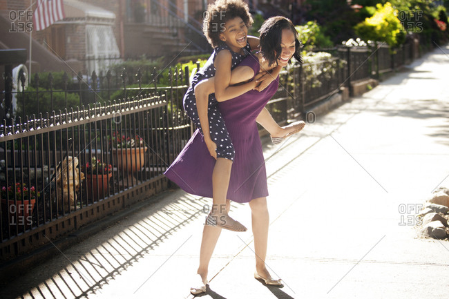 listener Substantially cell Mother giving daughter a piggy-back ride stock photo - OFFSET