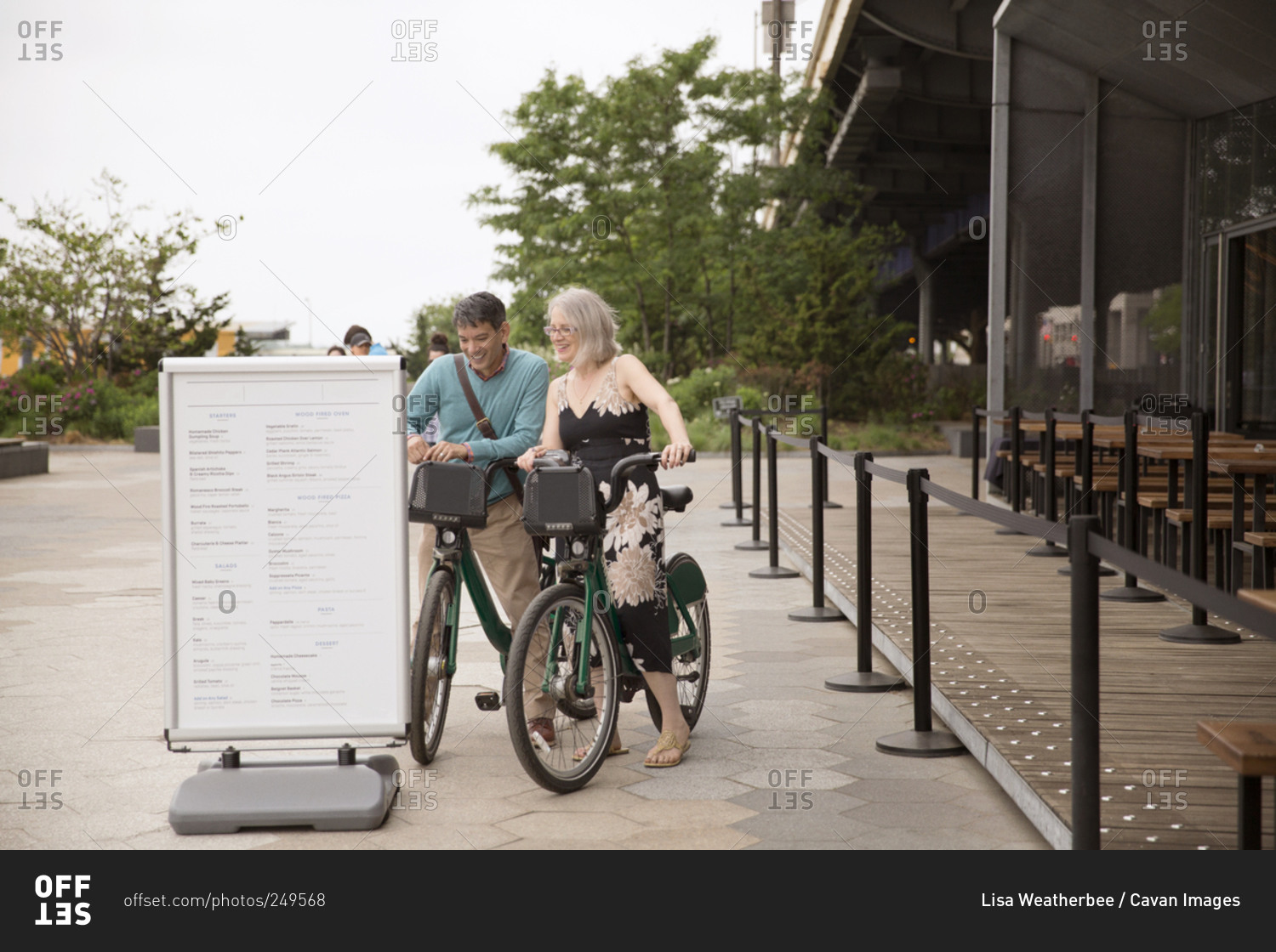 A couple riding shared bikes checks out a restaurant menu