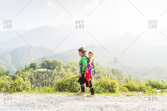 Sapa, Vietnam - May 10, 2015: Vietnamese woman carries her son on her back