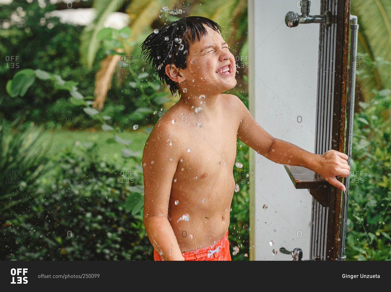 A boy smiles in an outdoor shower