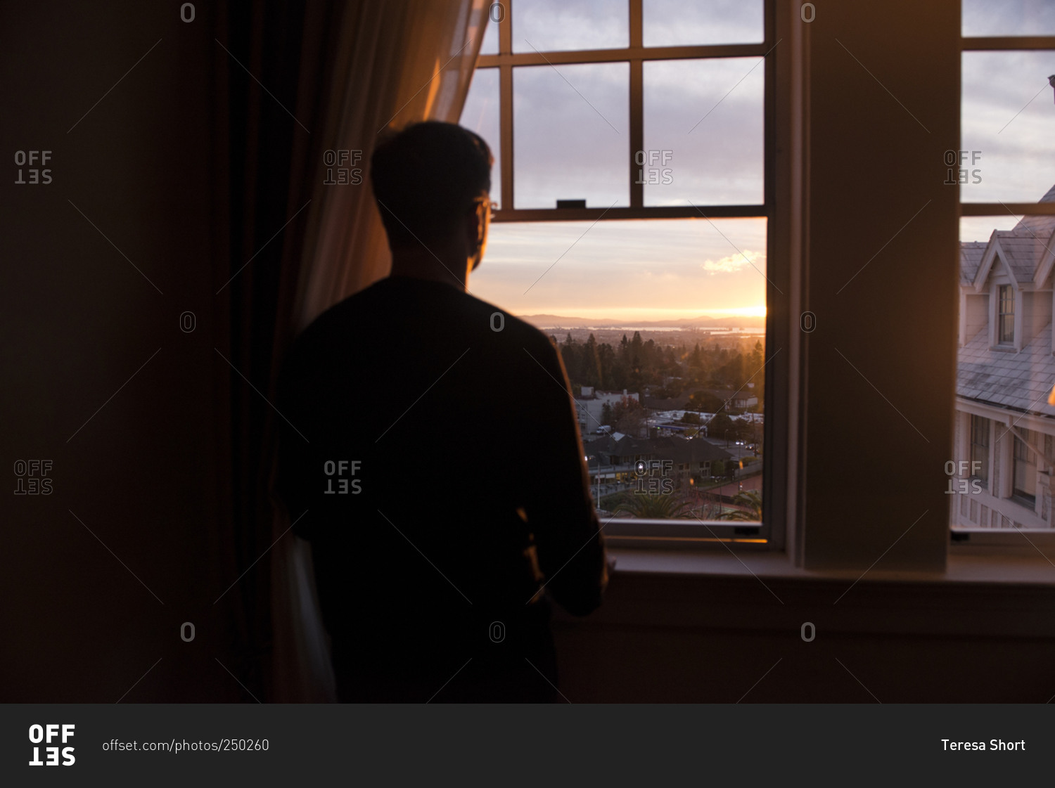 Man looking out a window at the sunset in Berkeley, California