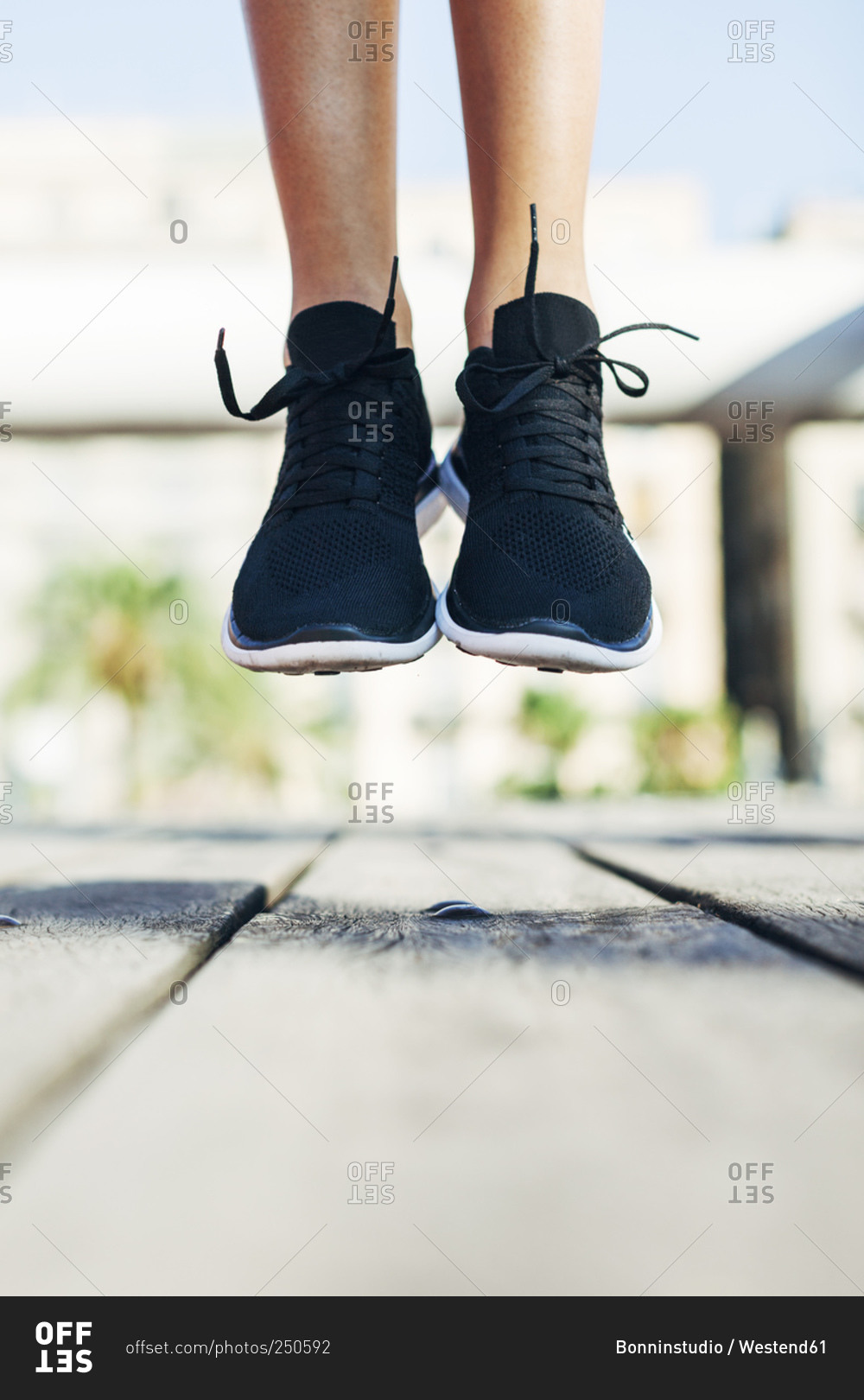 Sportive young woman wearing black sneakers jumping in the air
