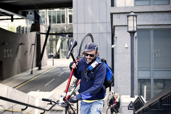 Cyclist carrying his bike up steps