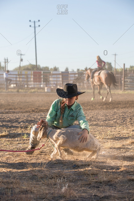 Young rodeo rider tying a goat