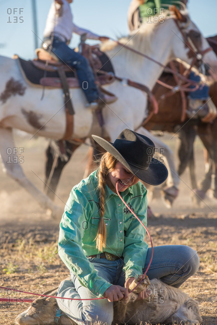 Teenage rodeo rider tying the legs of her captured goat