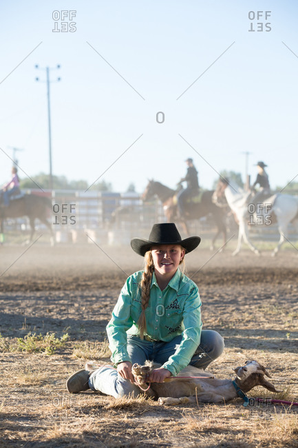 Portrait of a smiling teen rodeo rider with her roped goat